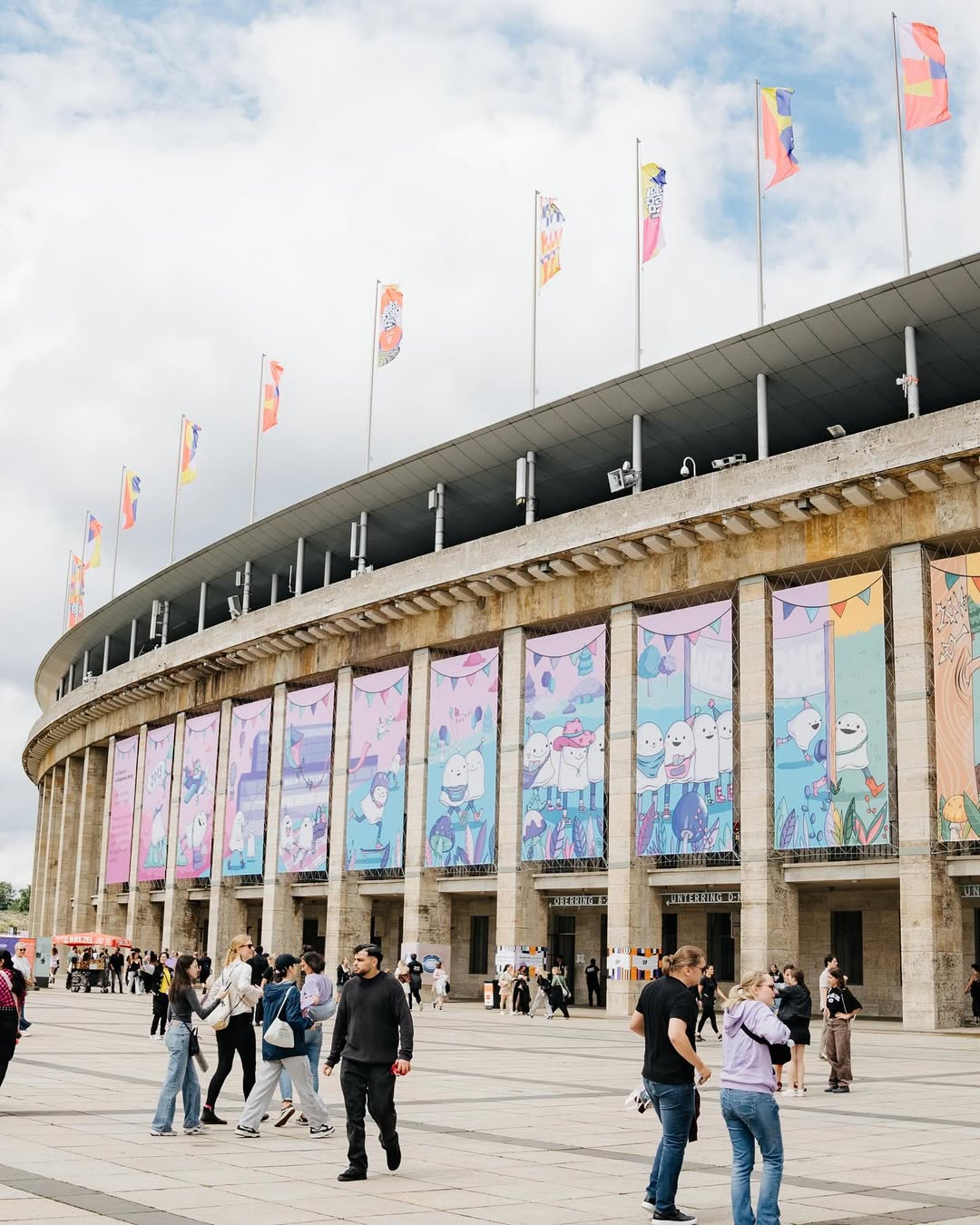 In a large comic strip circling the Olympiastadion, the curation of Lollapalooza Berlin, illustrated by Valérie Minelli, playfully traced the many relocations the festival experienced in its early years. Starting on the tarmac of the former Tempelhof Airport, passing through the scenic Treptower Park and the Hoppegarten racecourse, the little ghost characters encounter all kinds of companions before finally arriving at today’s location, the historic Olvmpiastadion and Olympiapark.
Did you discover the hidden details on site? 👻✨