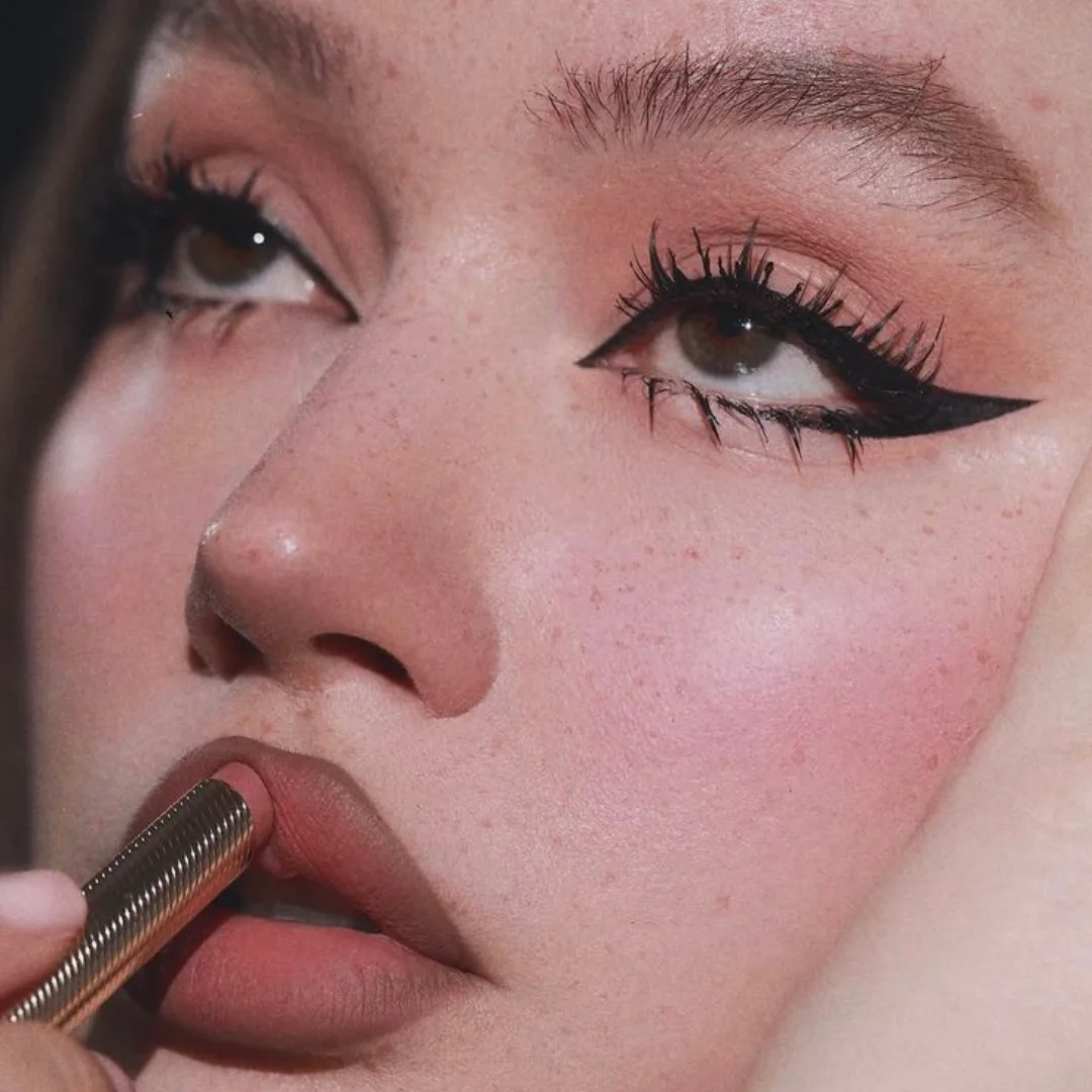 The cat eye liner in the image is a classic and timeless look that adds drama and sophistication to the eye. The thick, black liner is carefully applied to create a sharp, winged shape at the outer corner of the eye, which adds depth and dimension to the overall look. The liner is also extended slightly beyond the outer corner of the eye, which creates a sense of length and elegance. The combination of the cat eye liner with the long, luscious lashes and the subtle, natural-looking eyeshadow creates a beautiful and glamorous overall look.